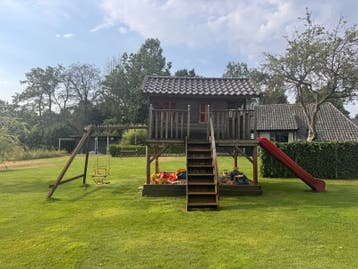 Houten speelhuisje met glijbaan en schommel