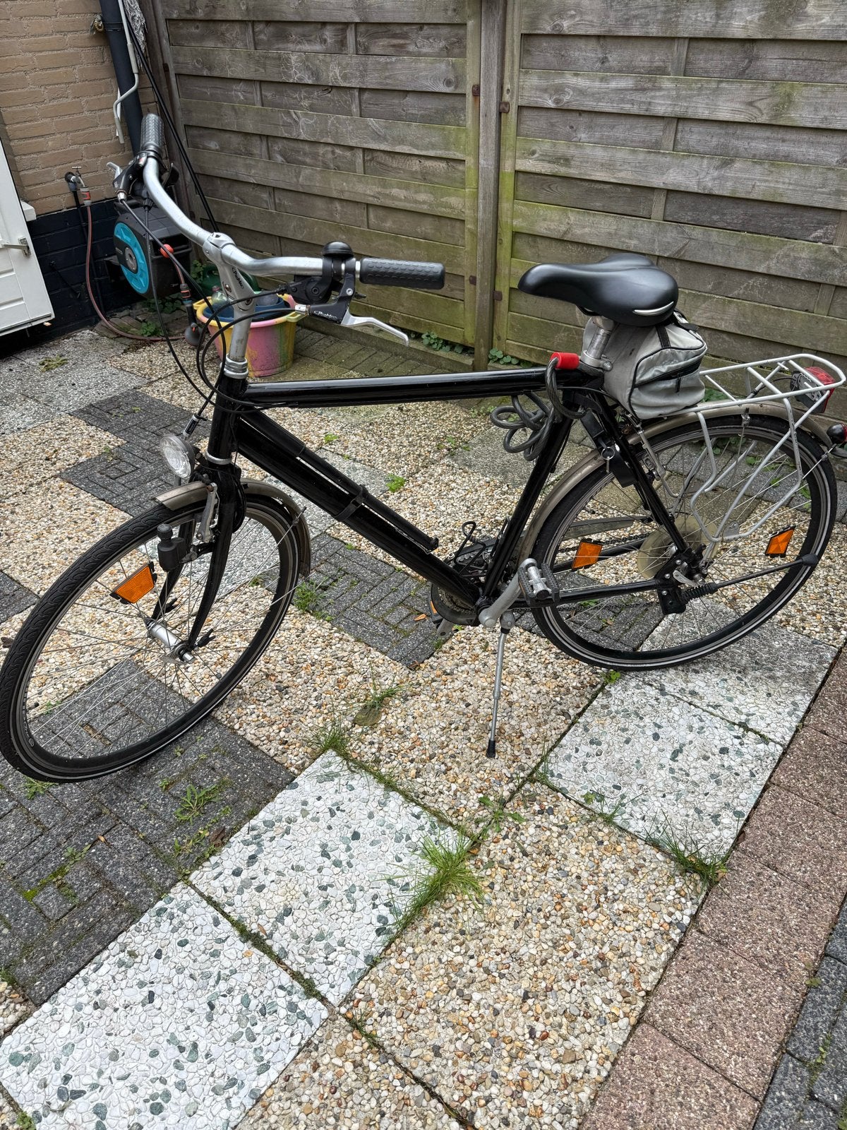Zwarte herenfiets met bagagedrager en spatborden