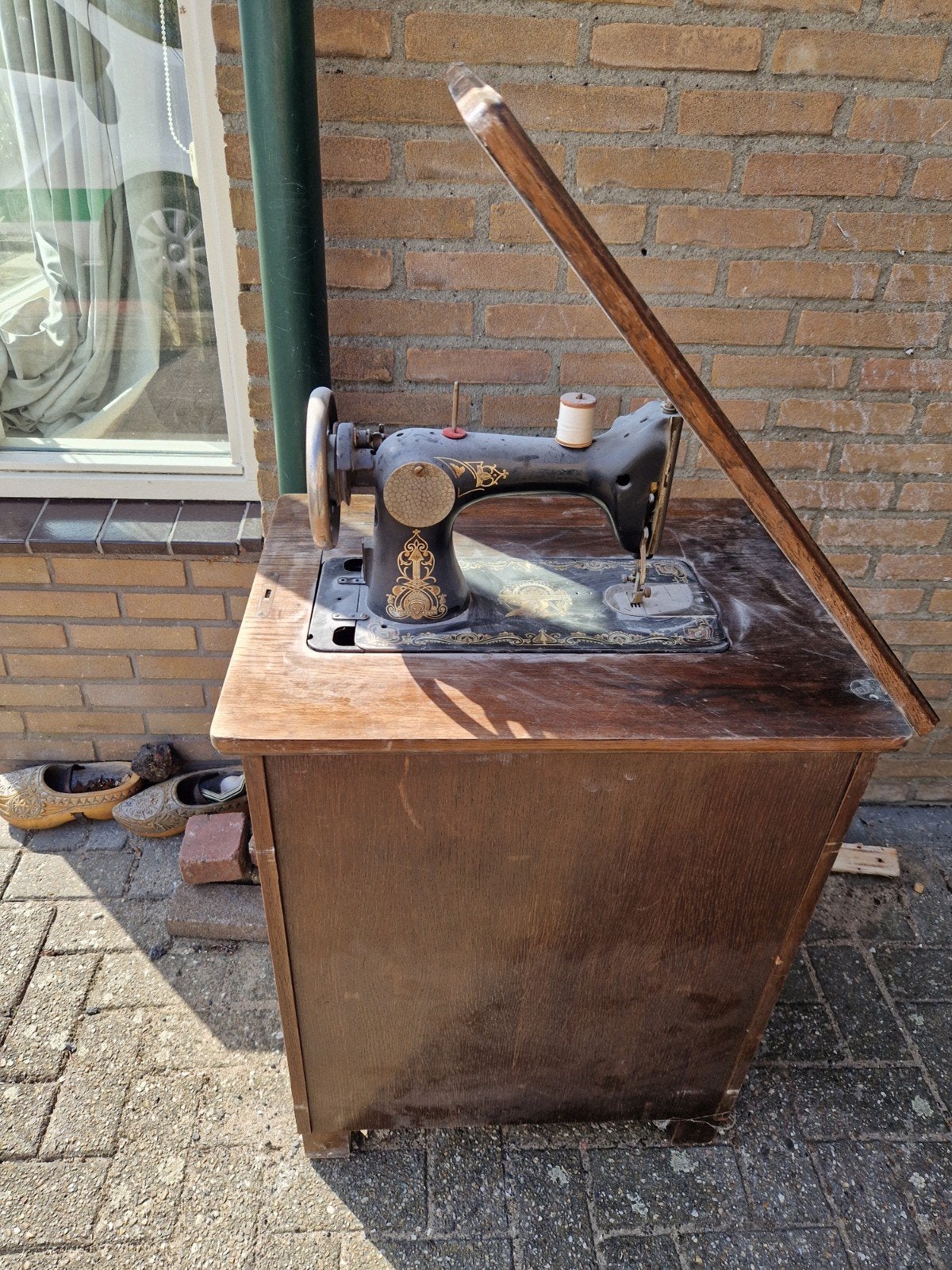 Antieke naaimachine met houten onderstel, Ophalen
