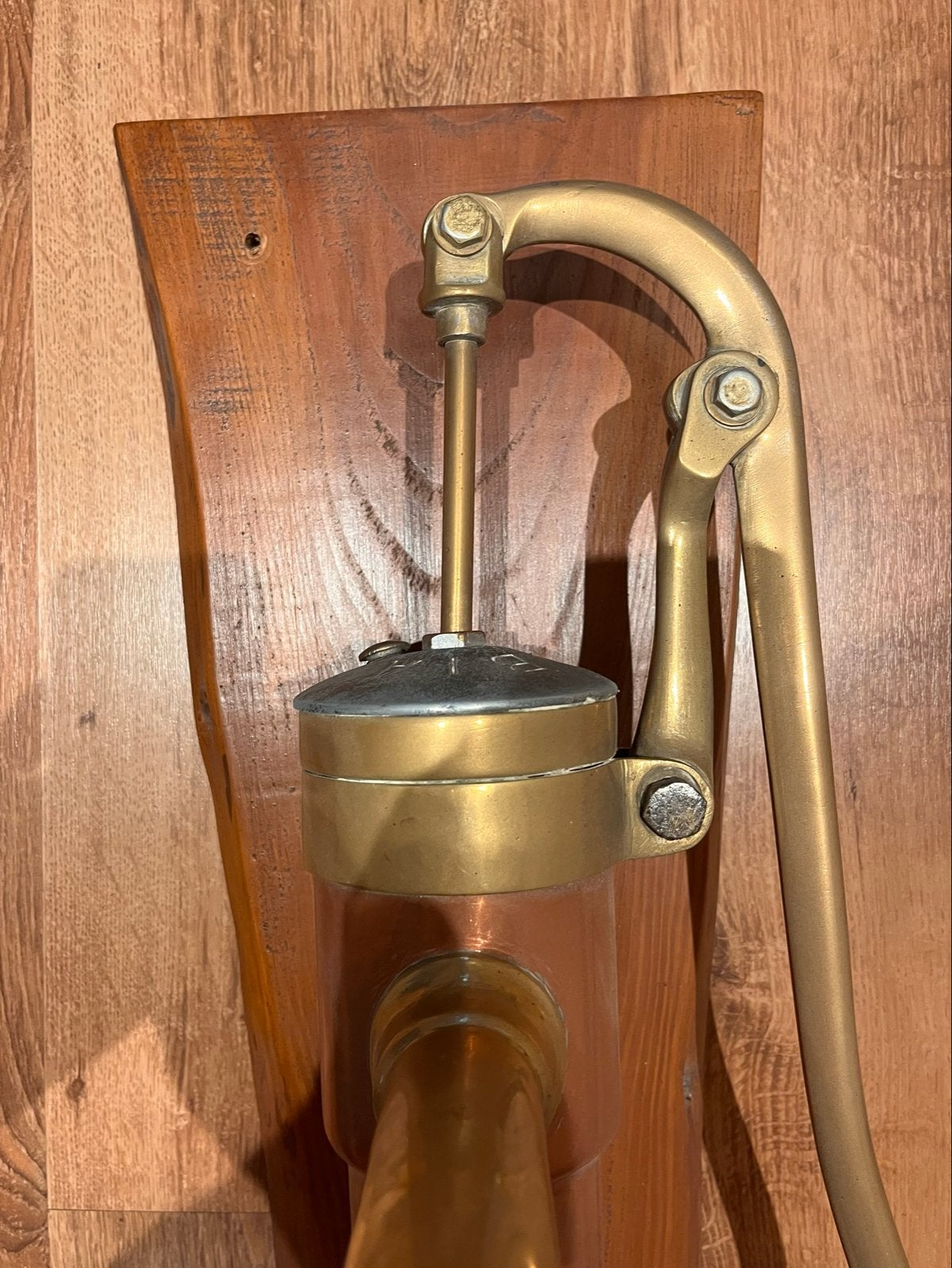 Antieke koperen waterpomp op houten plank, Ophalen, Brons