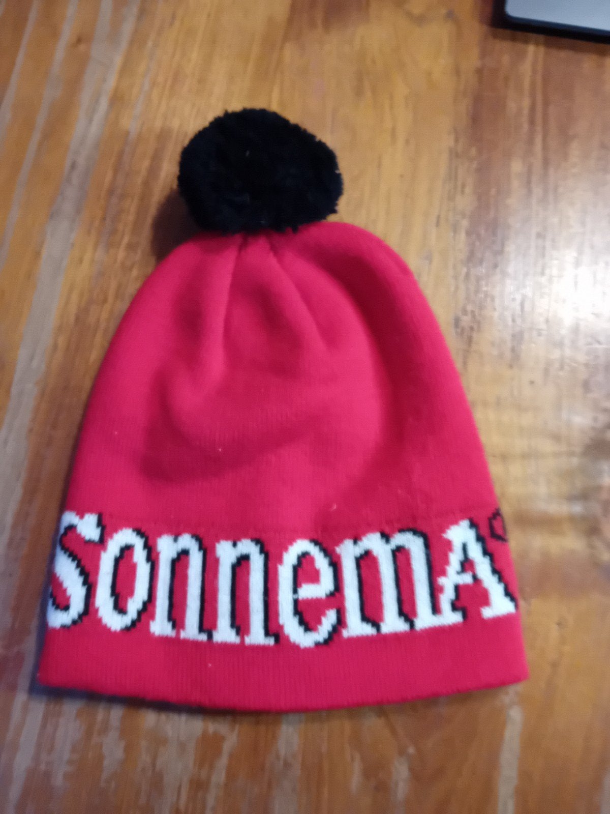 Rode muts met pompon en 'Sonnema' opdruk, Maat 38/40 (M), Sonnema, Ophalen of Verzenden, Zo goed als nieuw