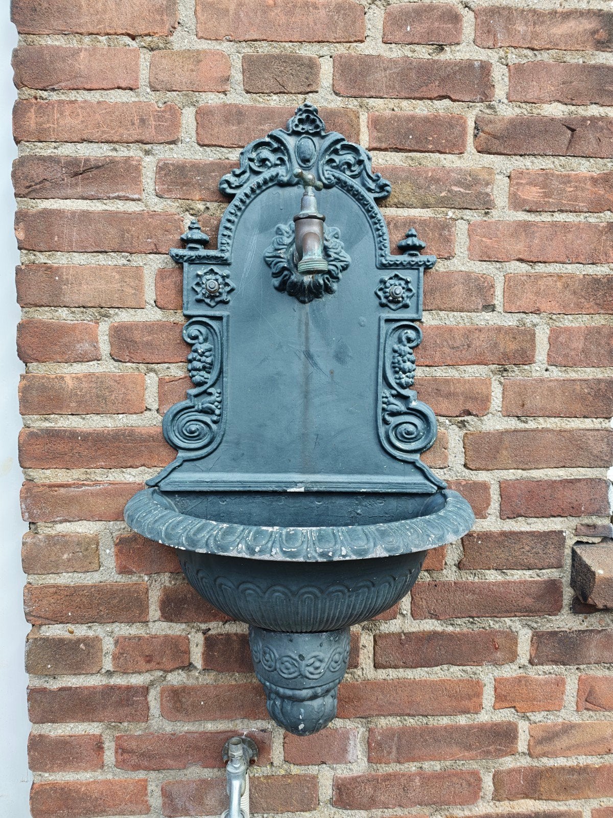 Antieke gietijzeren wandfontein met kraan, Ophalen