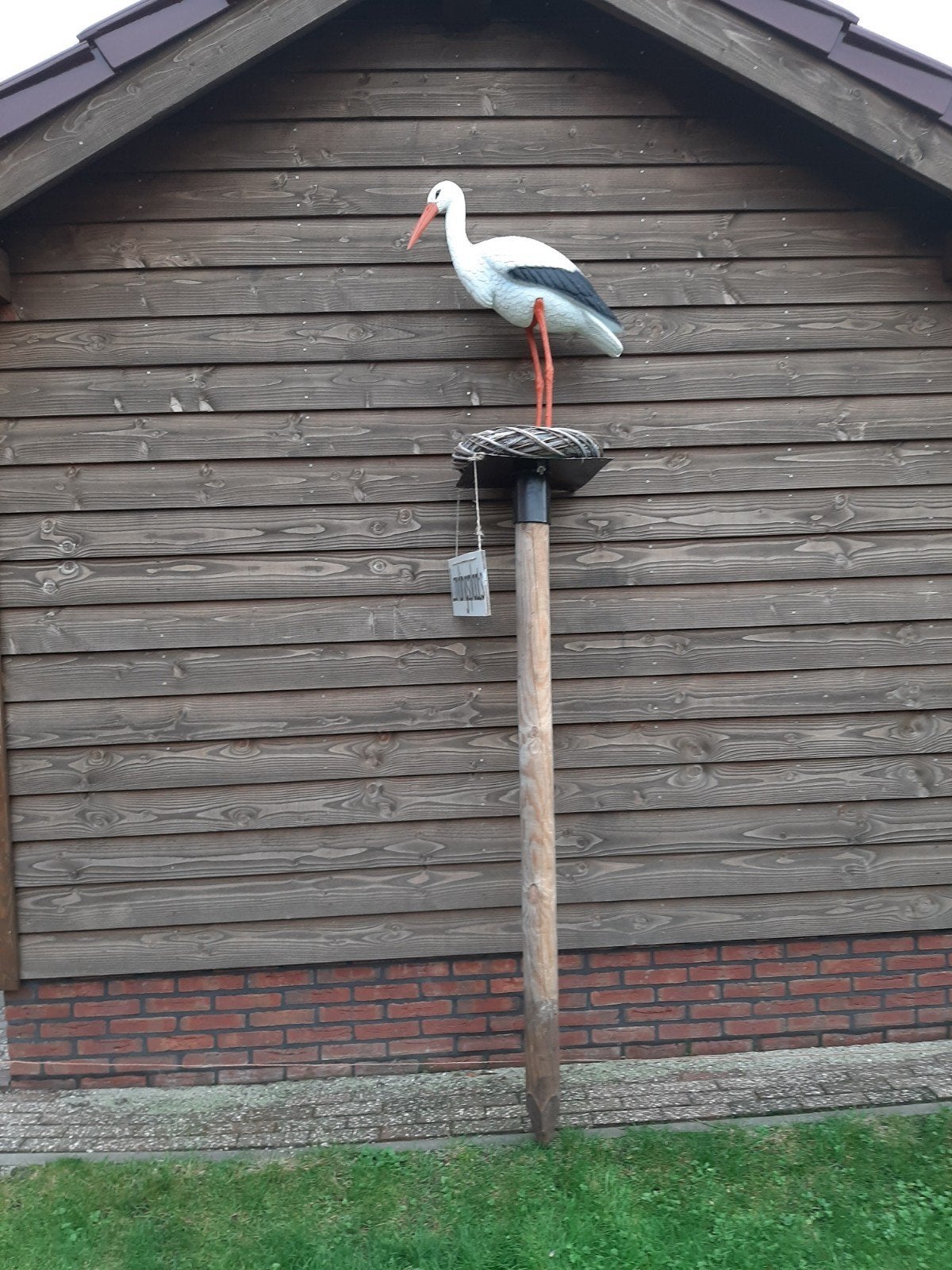 Ooievaar op nest met paal en pop en bordje landingsplaats, Ophalen