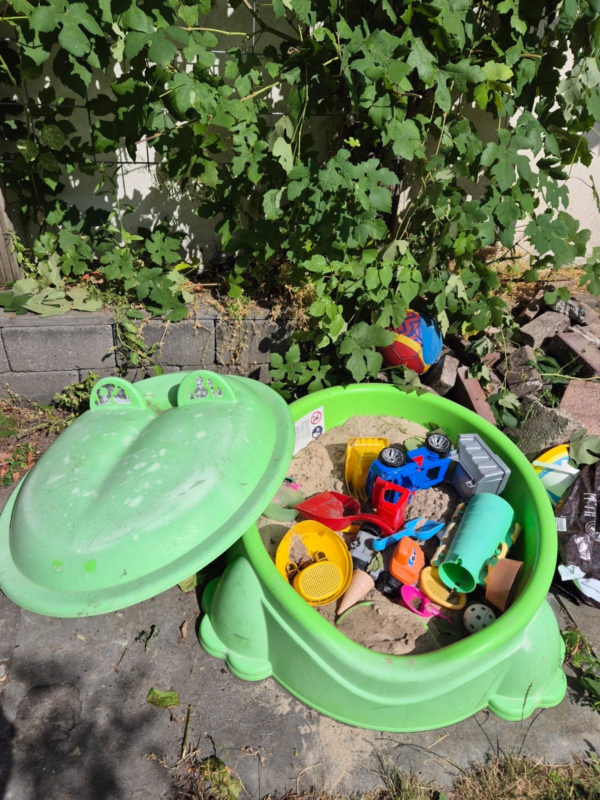 Groene zandbak met speelgoed, Ophalen