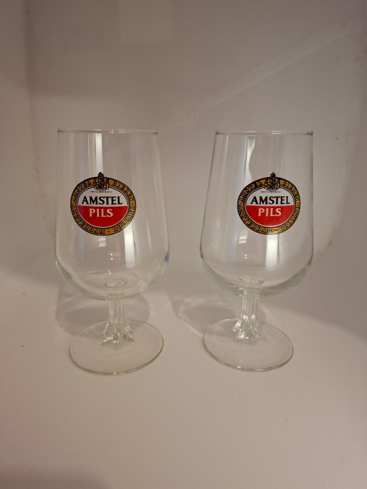 Set van 2 Vintage Amstel Pils Bierglazen op Voet (15 cm) – N, Ophalen of Verzenden, Zo goed als nieuw, Glas of Glazen, Amstel