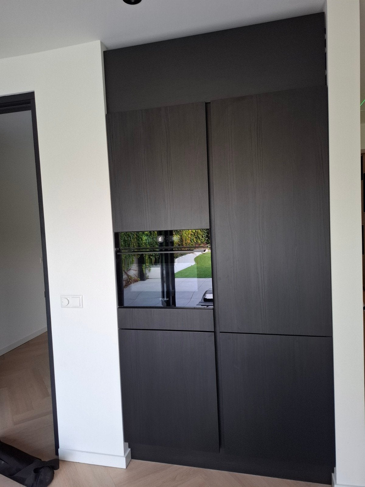 Zwarte keukenwand met combi oven en koel/vriescombinatie.