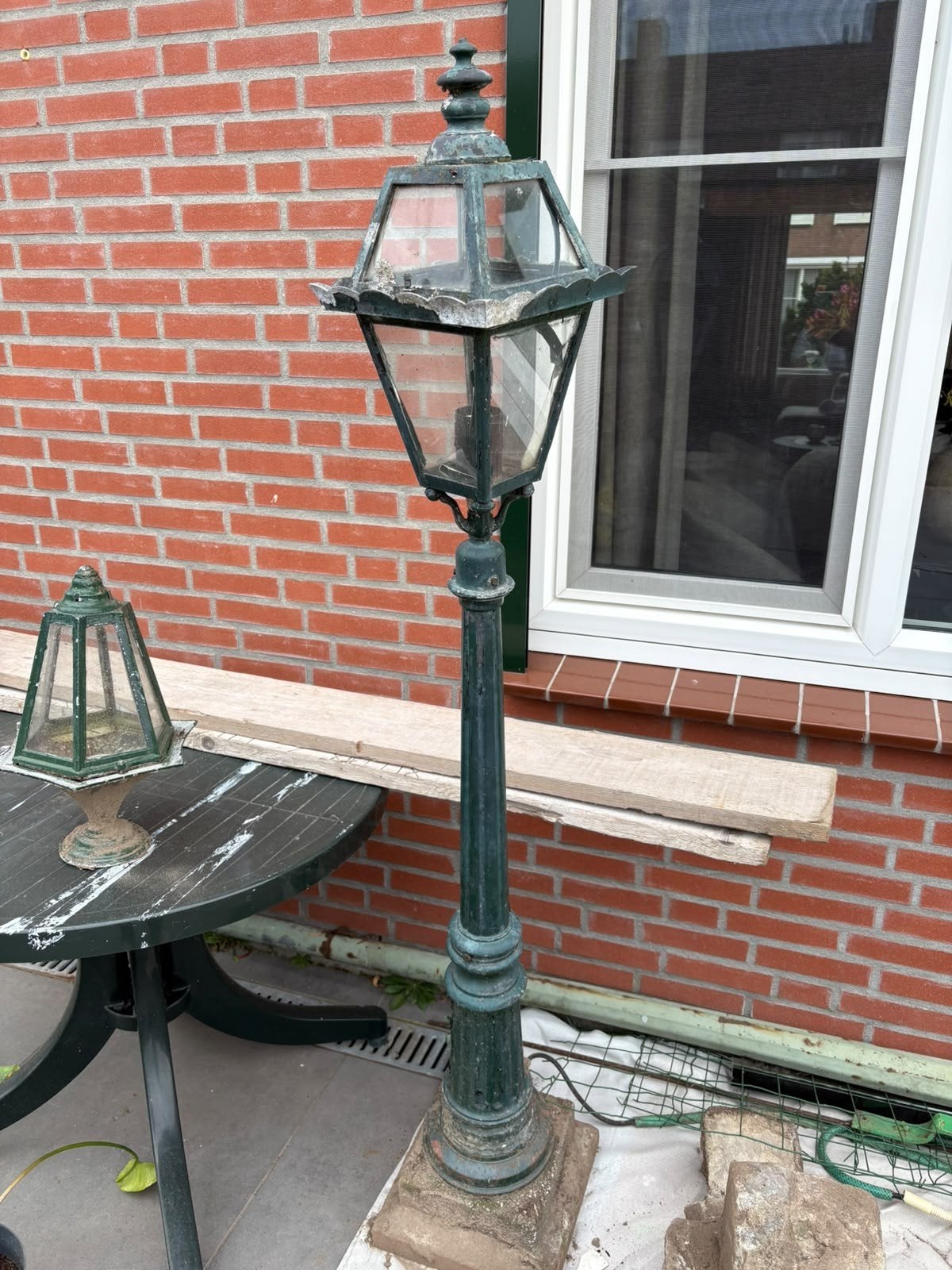 Antieke gietijzere straatlantaarn op betonnen voet, Ophalen