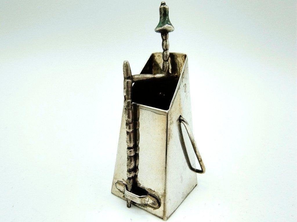 Zilveren miniatuur van een openhaardbak met porstok