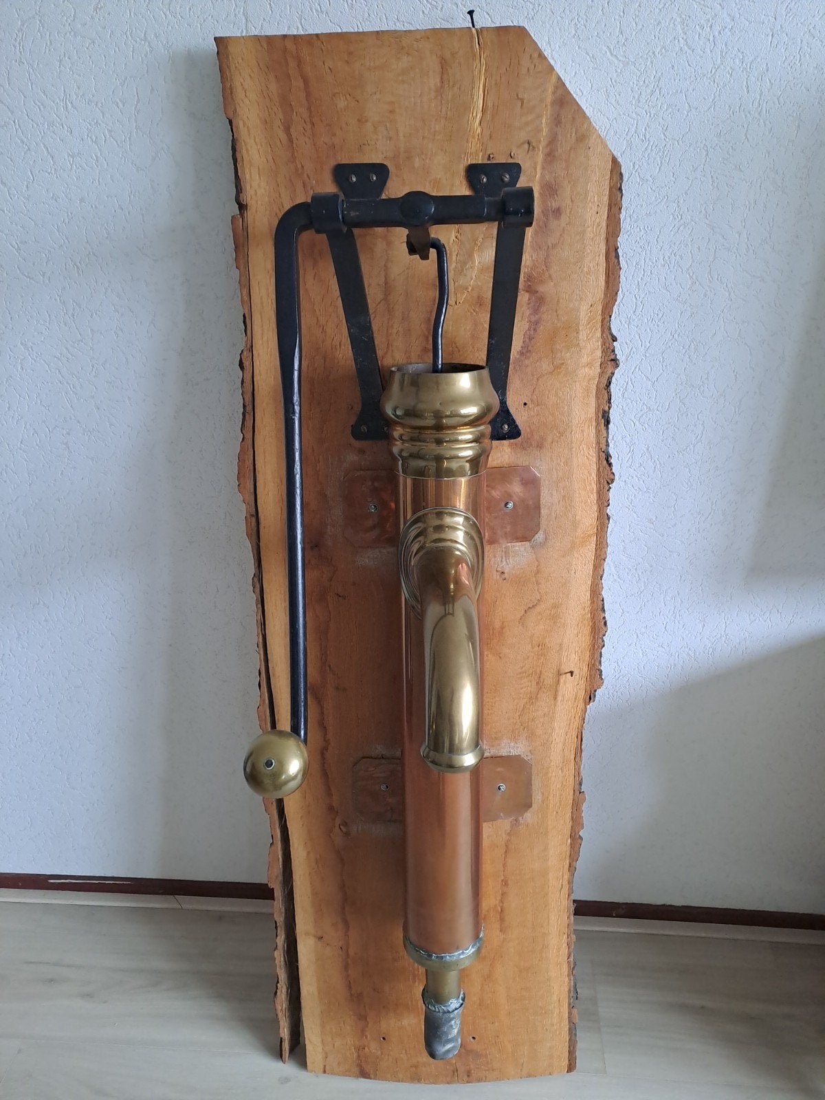 Antieke koperen waterpomp op houten plank, Ophalen