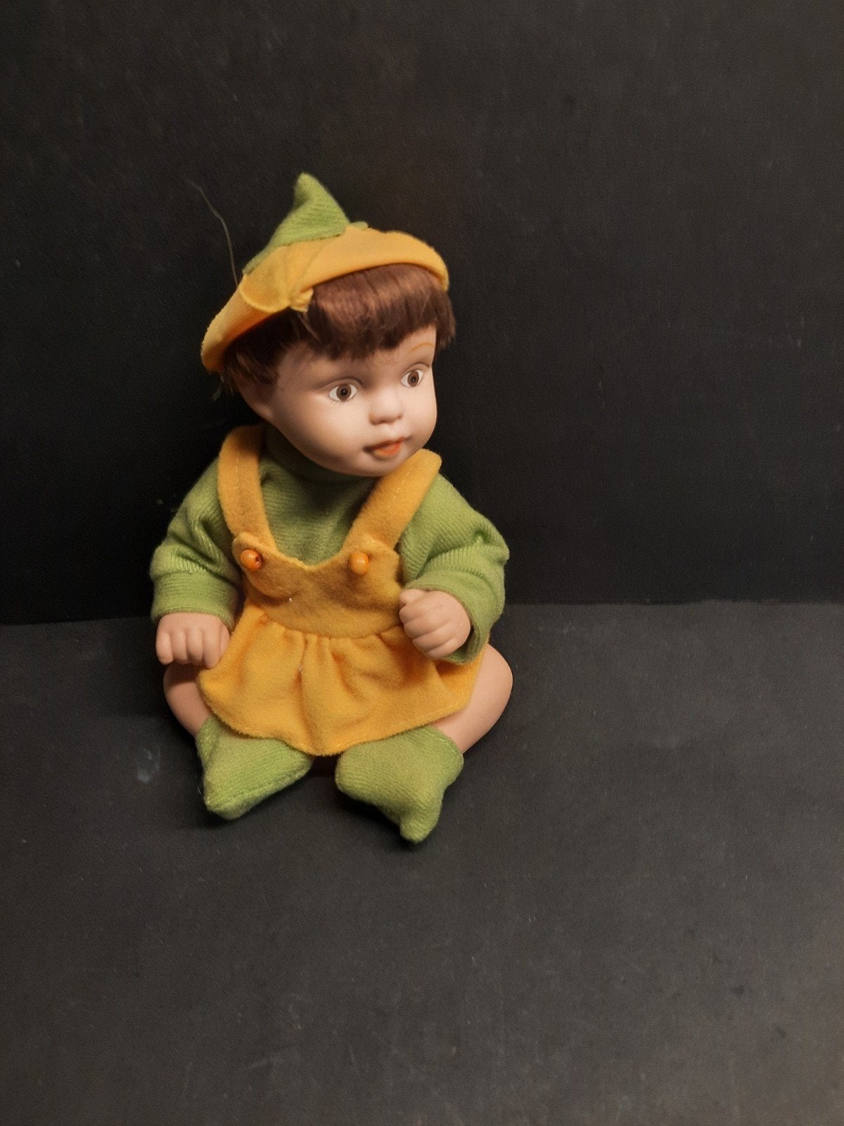 Schattige Vintage Porseleinen Babypop in Groen/Oranje Outfit, Verzamelen, Poppen, Gebruikt, Onbekend, Ophalen of Verzenden, Onbekend