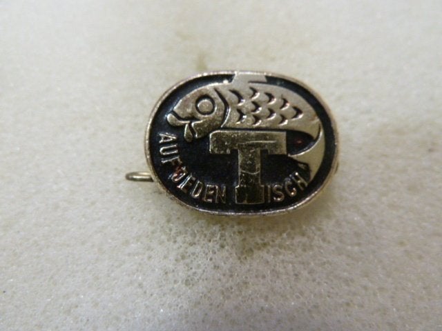 Vintage speld 'Auf jeden Tisch' met vis en letter T, Ophalen of Verzenden, Gebruikt, Overige onderwerpen, Speldje of Pin