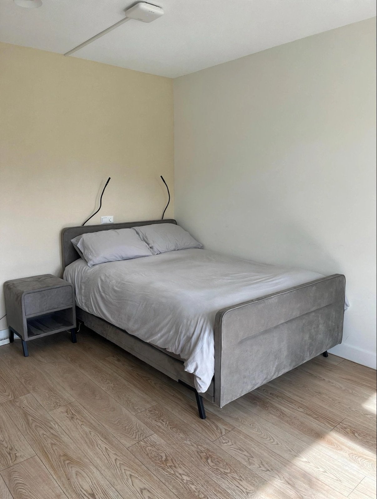 Tweepersoonsbed met stoffen bekleding en nachtkastje