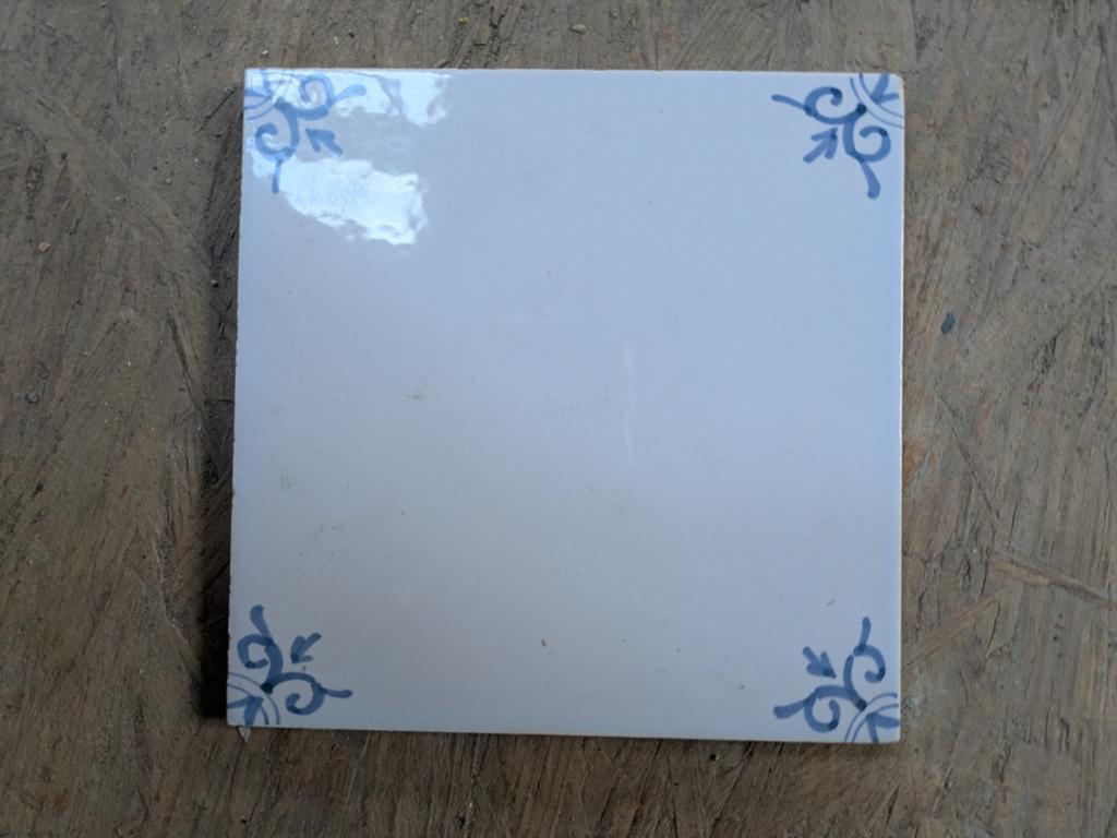 Antieke wit-blauwe tegel met hoekmotief, Ophalen of Verzenden