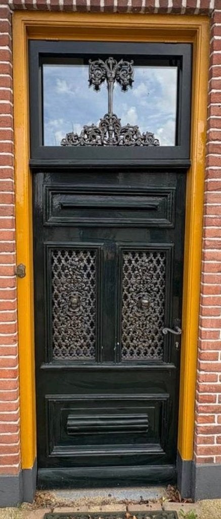 Antieke voordeur met roosters en bovenlicht zonder kozijn.