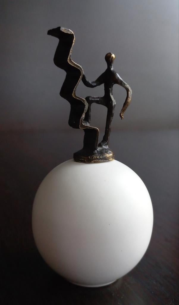 Beeldje figuur die een zigzaglijn beklimt op een witte bol, Antiek en Kunst, Ophalen of Verzenden, Brons