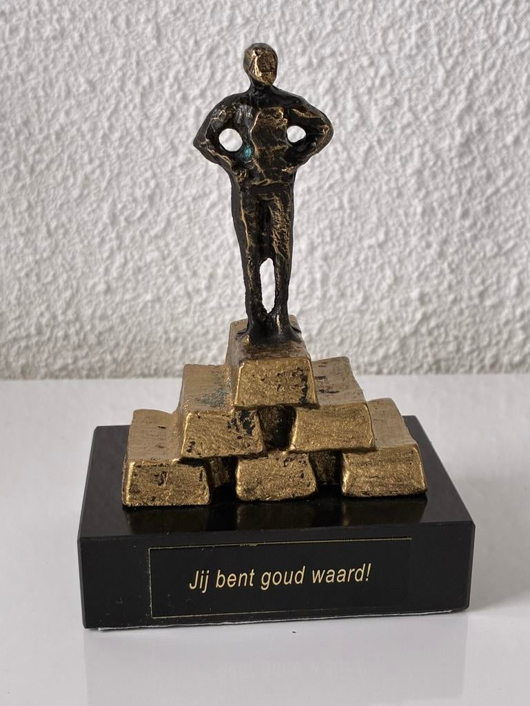 Een beeldje van een persoon op 6 figuurlijke goudstaven., Ophalen of Verzenden