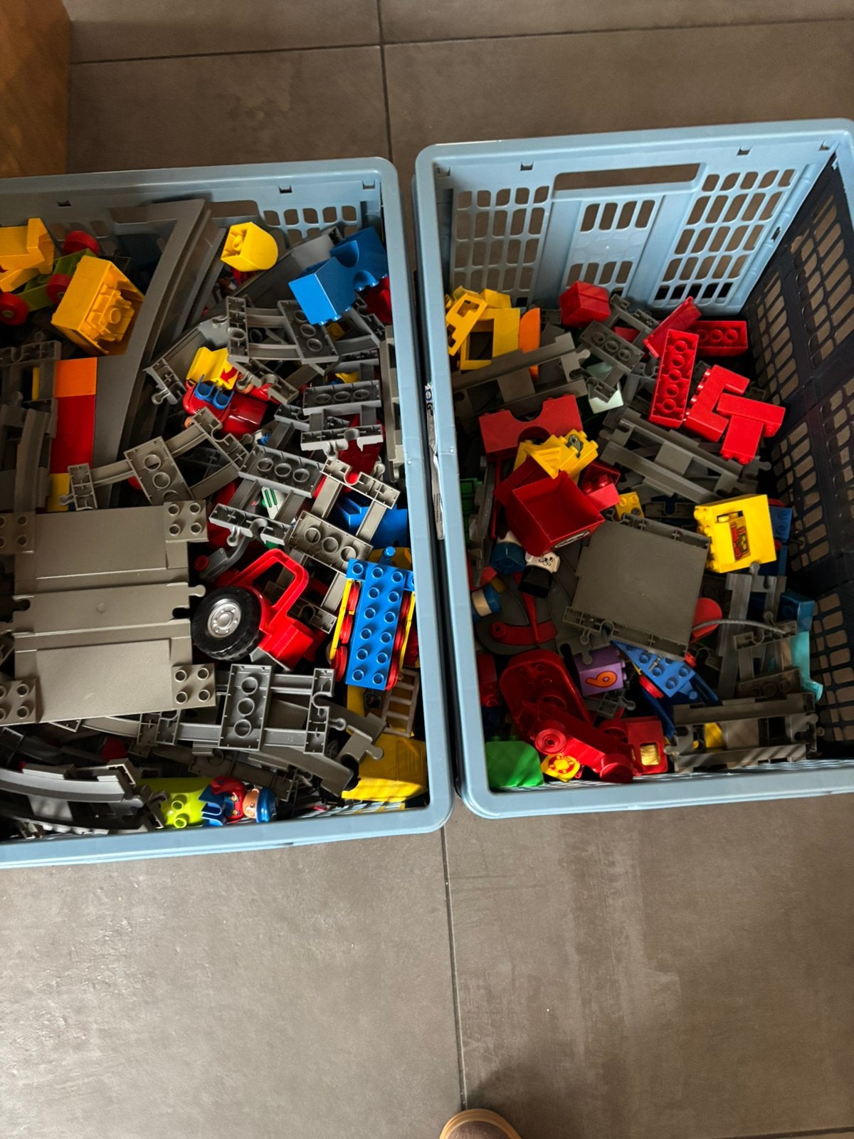 Anderhalve krat met duplo met treinrails, blokken en wagons