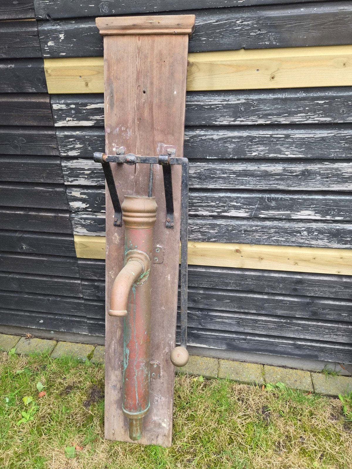 Antieke koperen waterpomp op houten plank, Ophalen