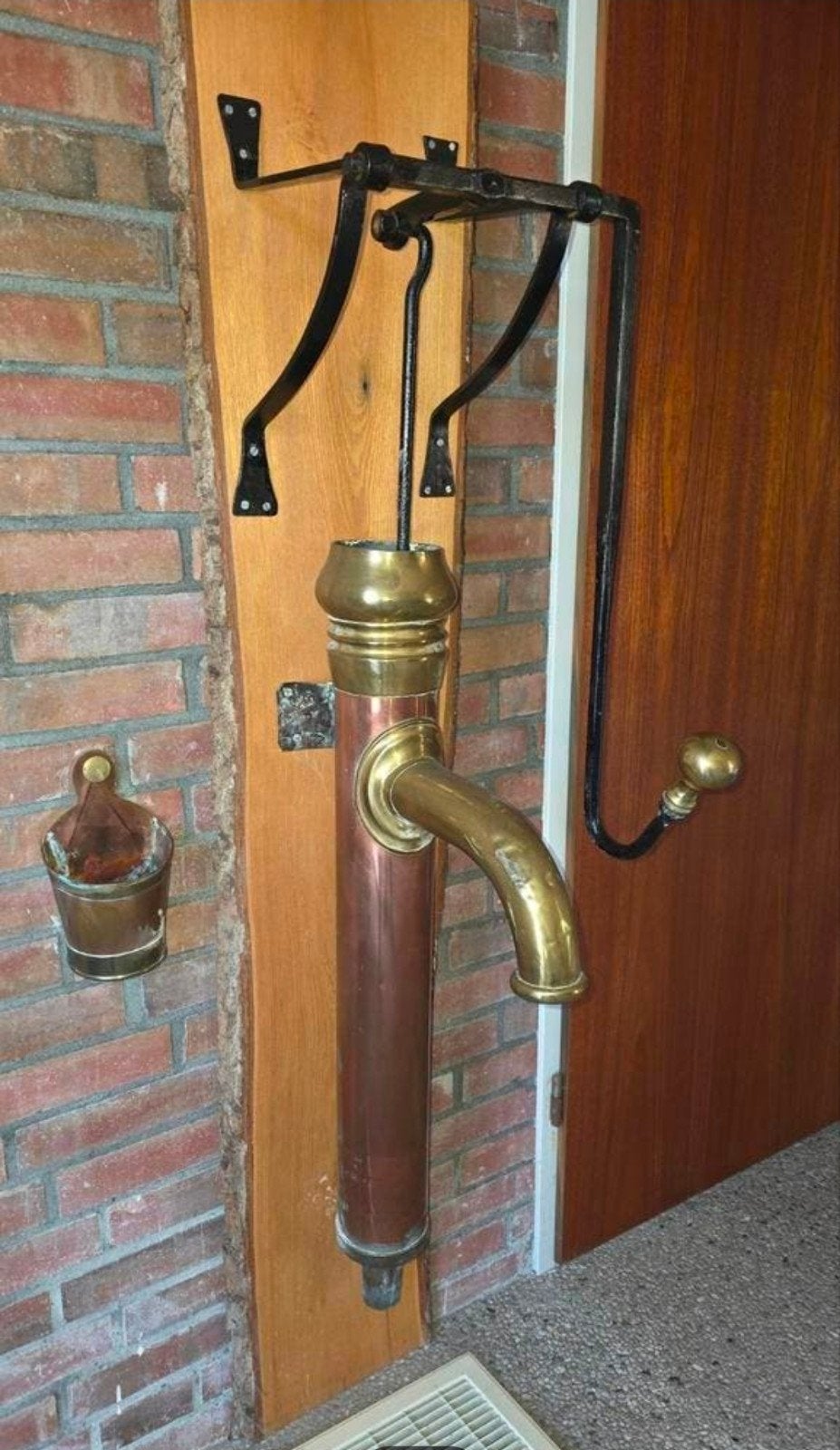 Antieke koperen waterpomp op houten paneel, Ophalen