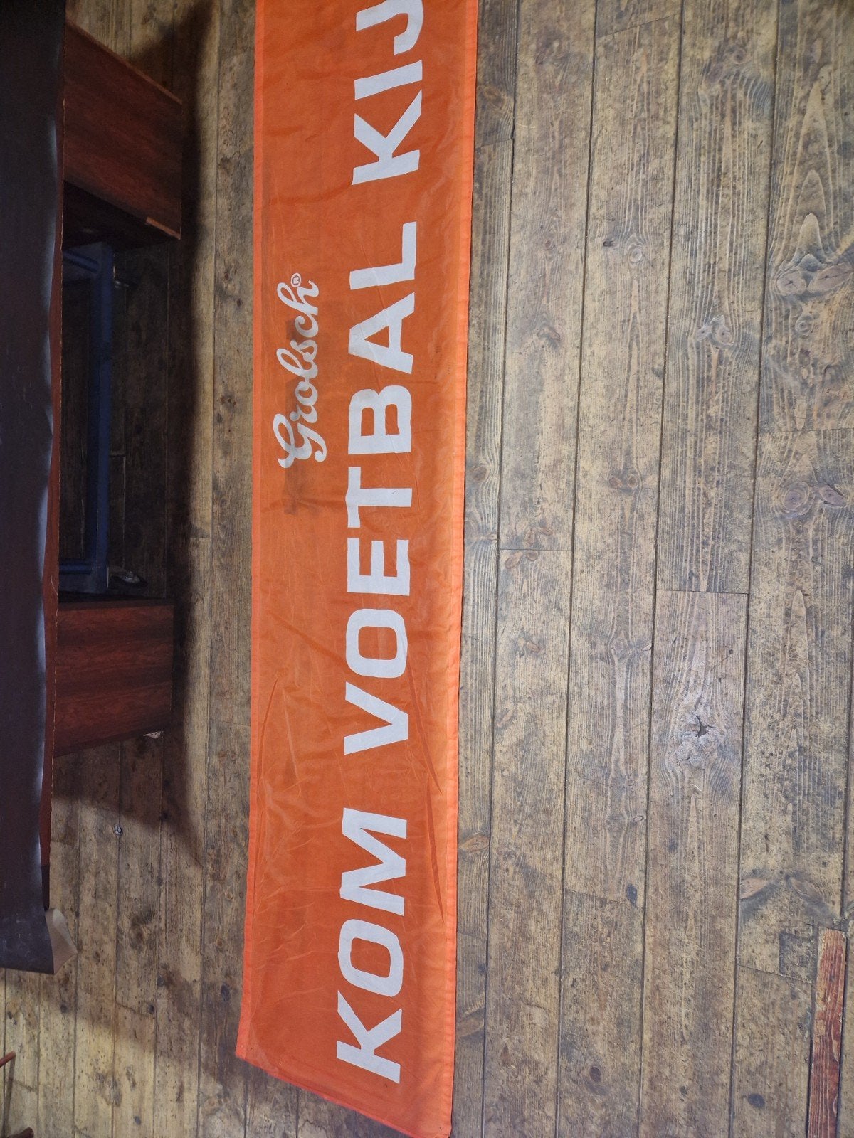 Oranje grolsch spandoek met de titel.  Kom voetbal kijken, Ophalen