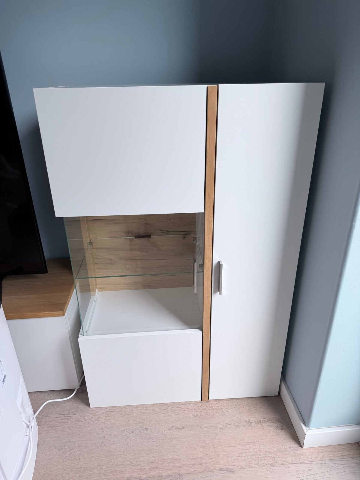 Foto 6 van Witte wandkast met glazen vitrine en houten accenten