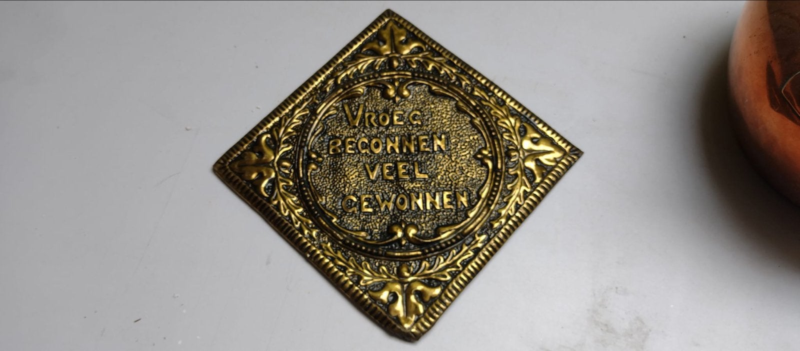 Antieke koperen plaquette 'Vroeg begonnen veel gewonnen', Ophalen