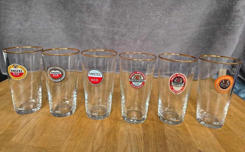 Amstel bierglazen set. 6 verschillende logos 1875-1980, Verzamelen, Ophalen of Verzenden, Zo goed als nieuw, Glas of Glazen, Amstel
