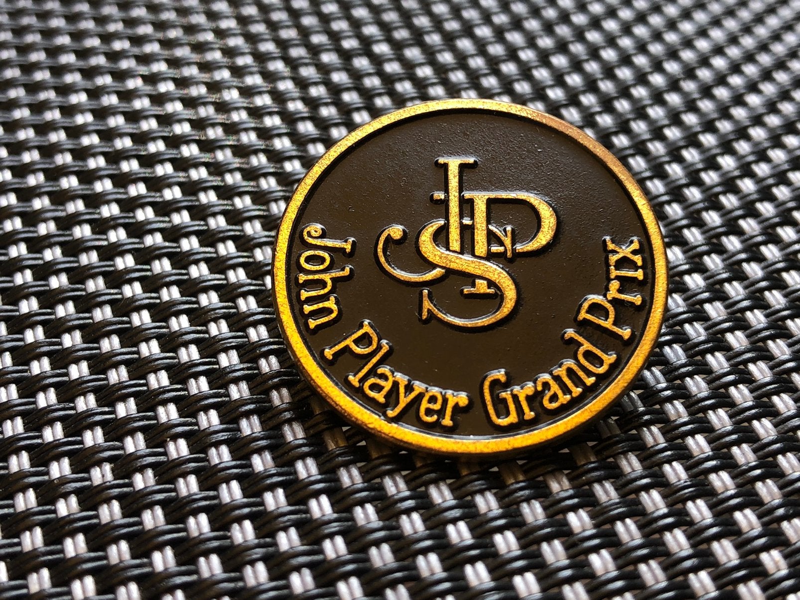 Zwarte broche met goudkleurige tekst John Player Grand Prix, Verzamelen, Ophalen of Verzenden, Zo goed als nieuw, Merk, Button