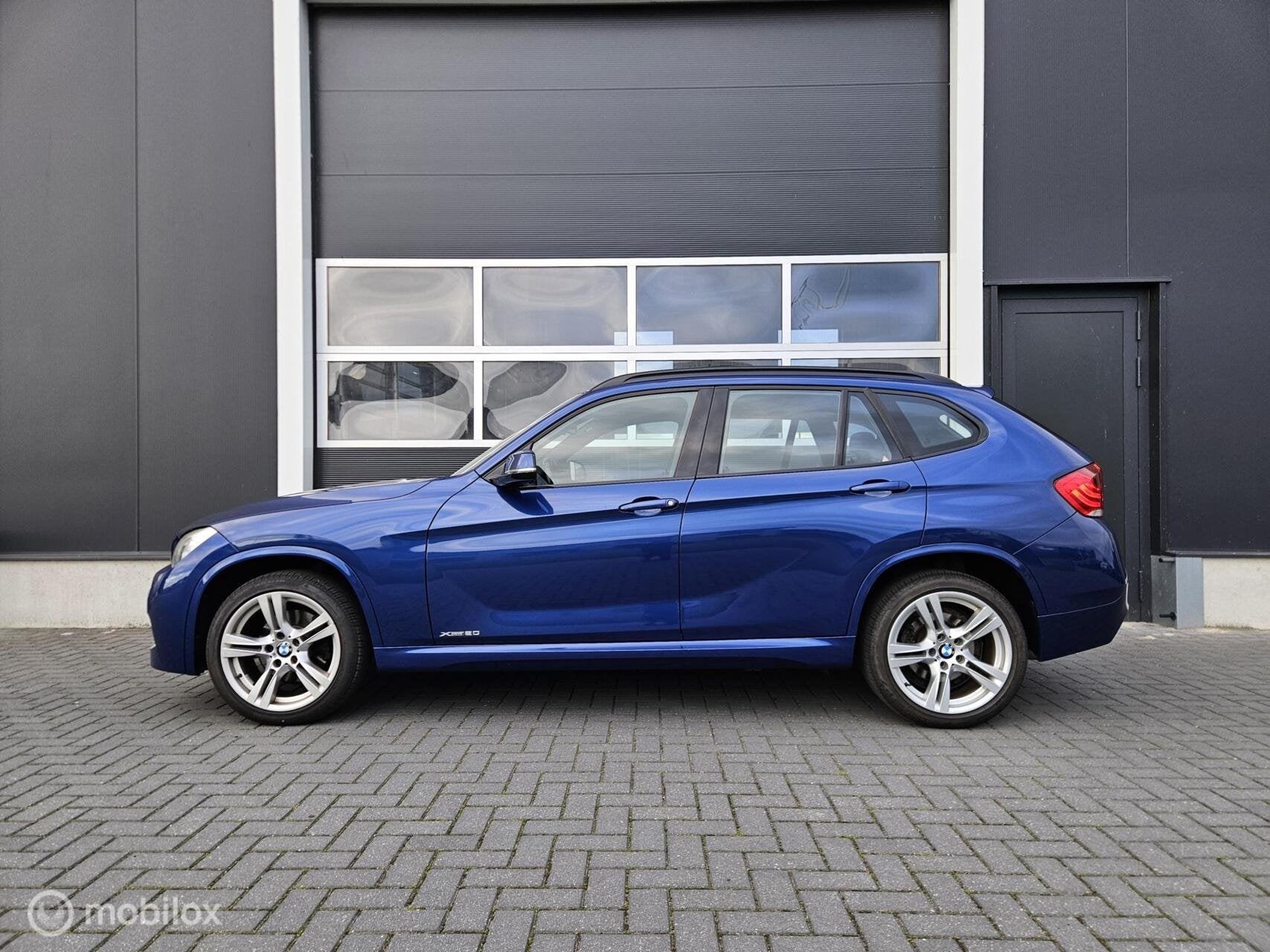 BMW X1 20i M-Pakket Le Mans Blue 184PK Nieuwe APK | Trekhaak, Auto's, Gebruikt, Zwart, 4 cilinders, 2000 kg
