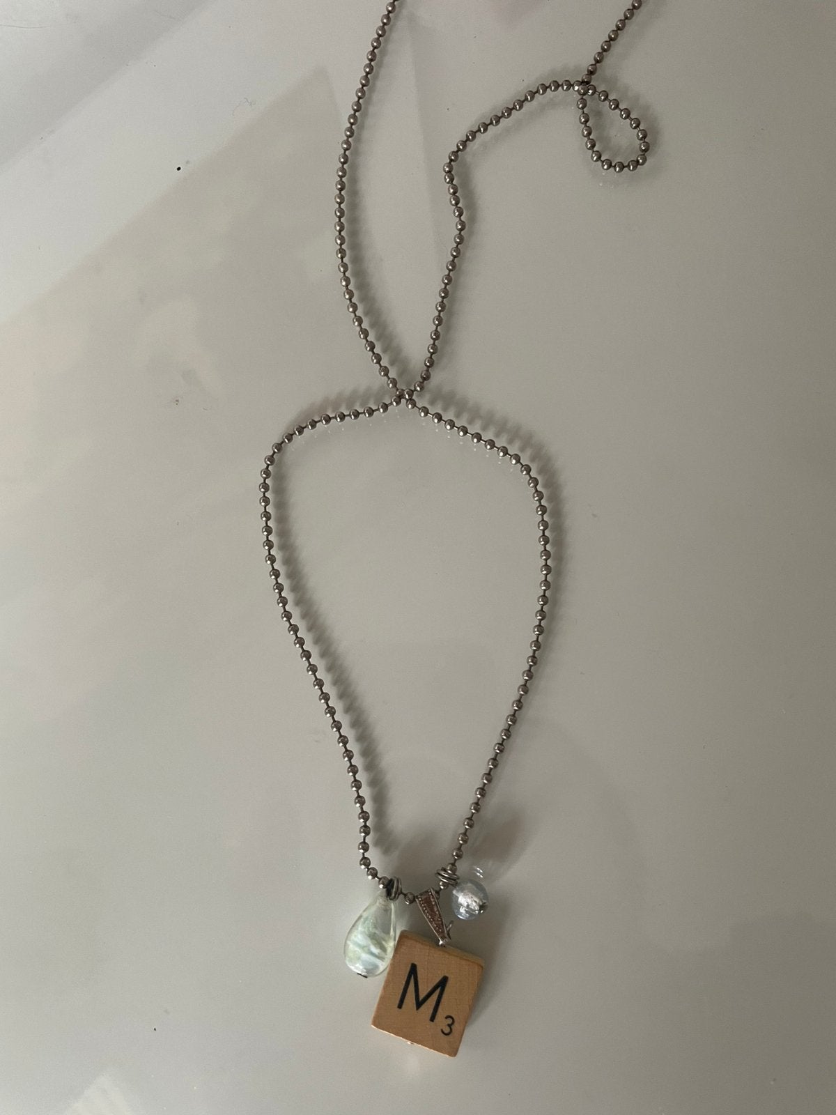 Lange zilverkleurige ketting met M-bedel & mooie hangers, Gebruikt, Ophalen of Verzenden, Zilver, Overige materialen