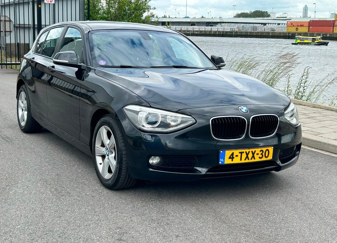 BMW 1-Serie 116i 136PK 5D Aut.NAVI PDC LED, Auto's, BMW, 4 cilinders, Zwart, Origineel Nederlands, 1200 kg