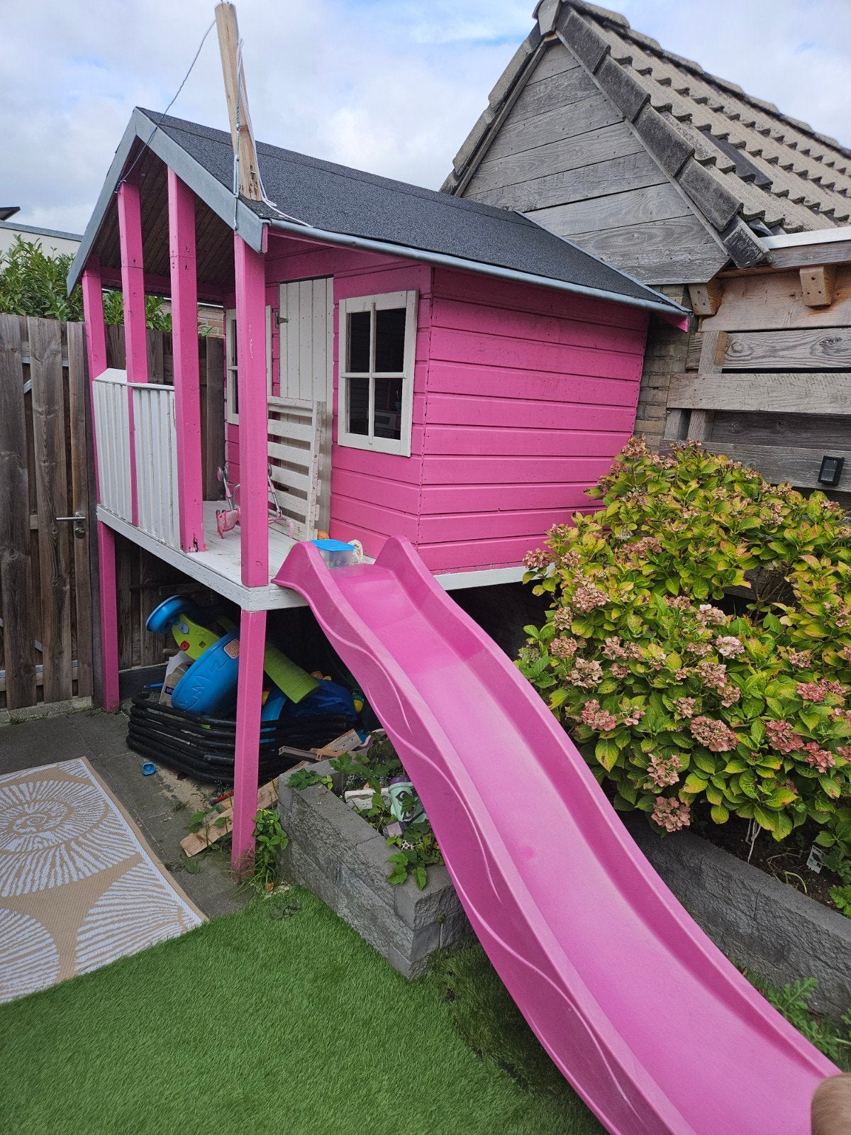 Roze speelhuisje op palen met glijbaan en trap, Ophalen, Gebruikt, Hout