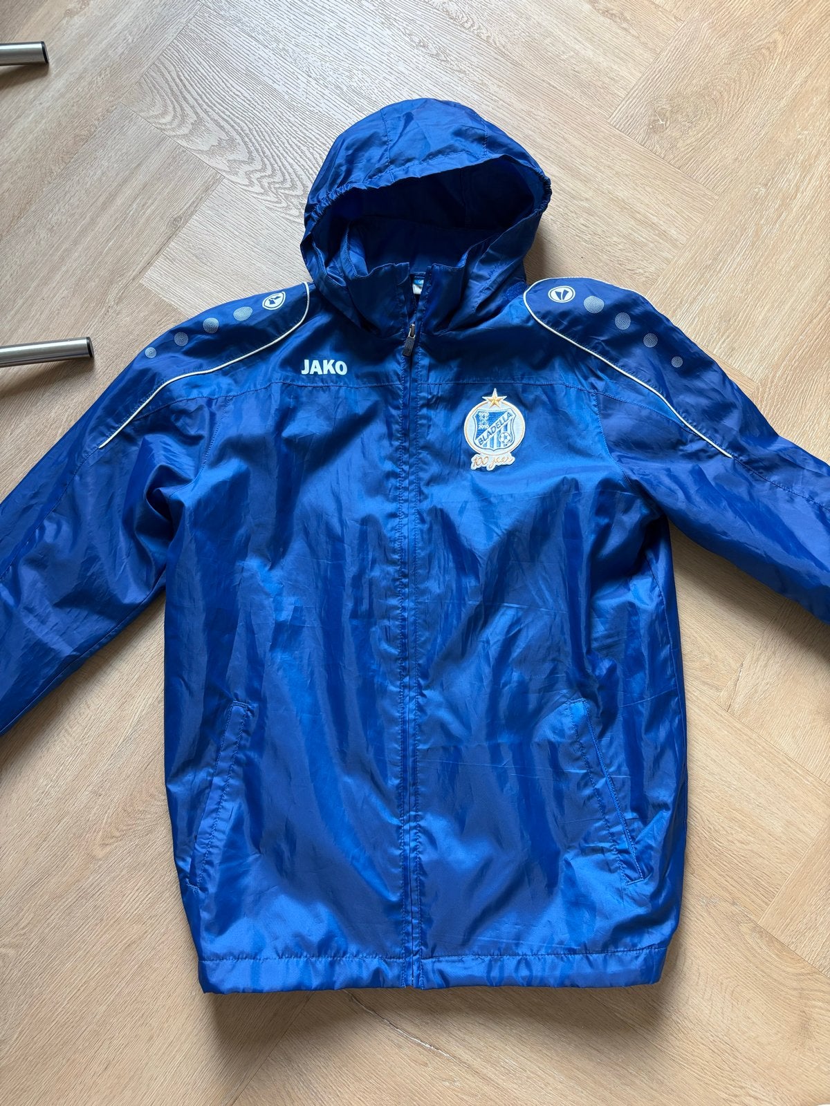 Jako Bladella 100 jaar voetbal regenjas - Maat M, Blauw, Ophalen of Verzenden, Zo goed als nieuw, Voetbal