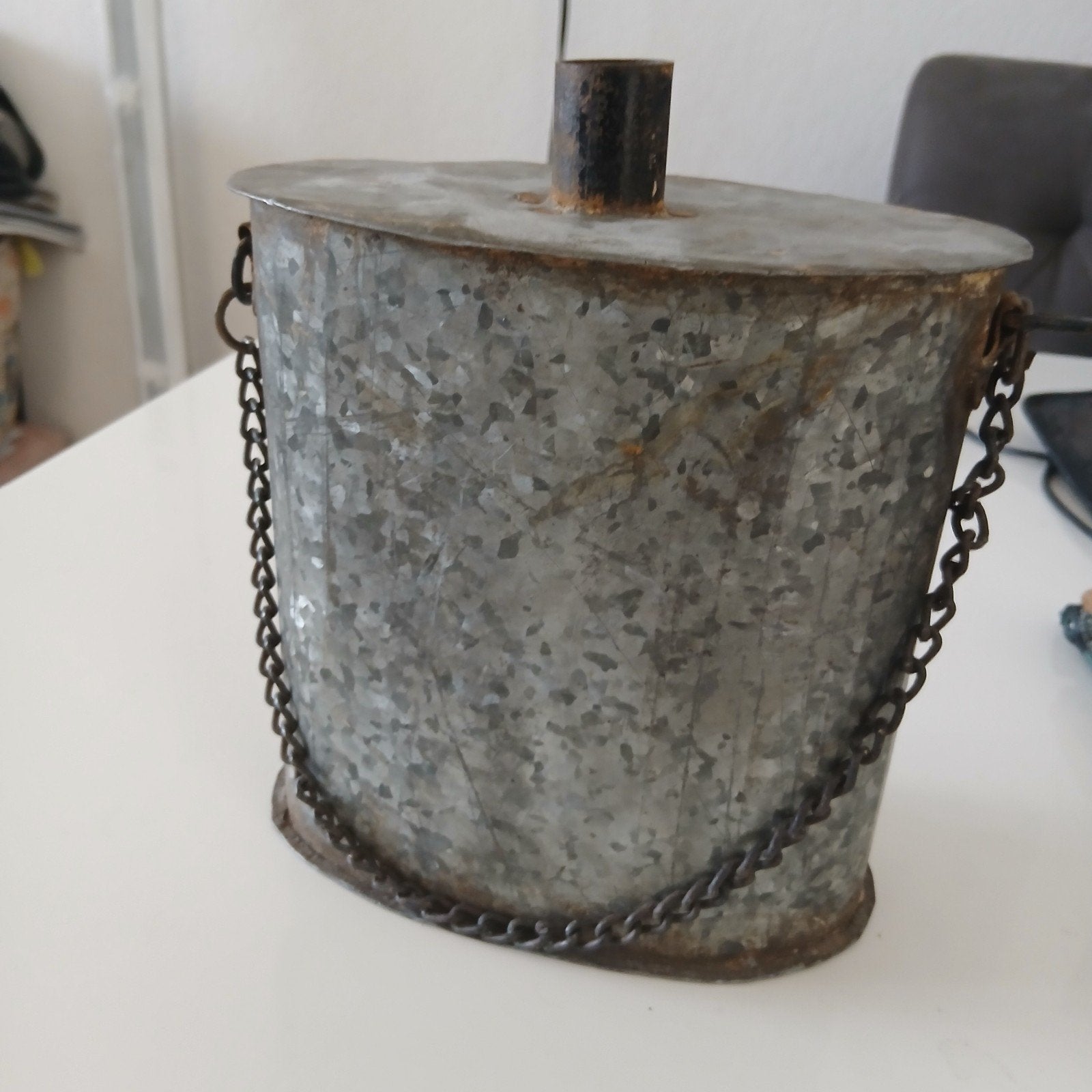 Oude metalen waterkruik met ketting, Ophalen