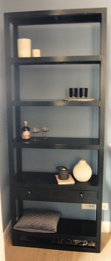 Hoge zwarte open kast met brede planken en lade