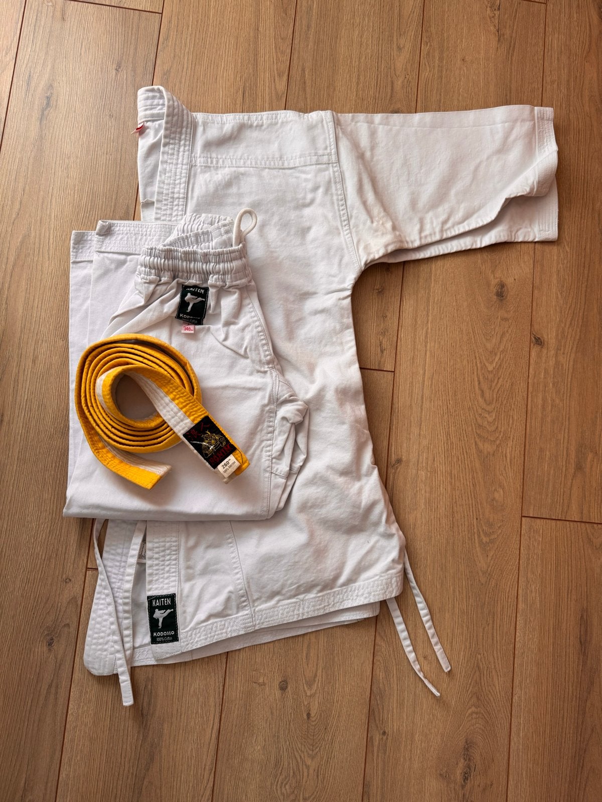 Karatepak Kaïten Kodomo 140cm met wit/gele band, Gebruikt, Vechtsportpak, Karate, Maat M