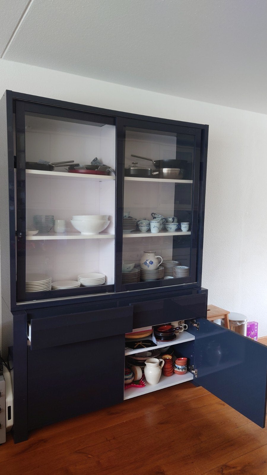 Donkerblauwe vitrinekast met schuifdeuren en lades