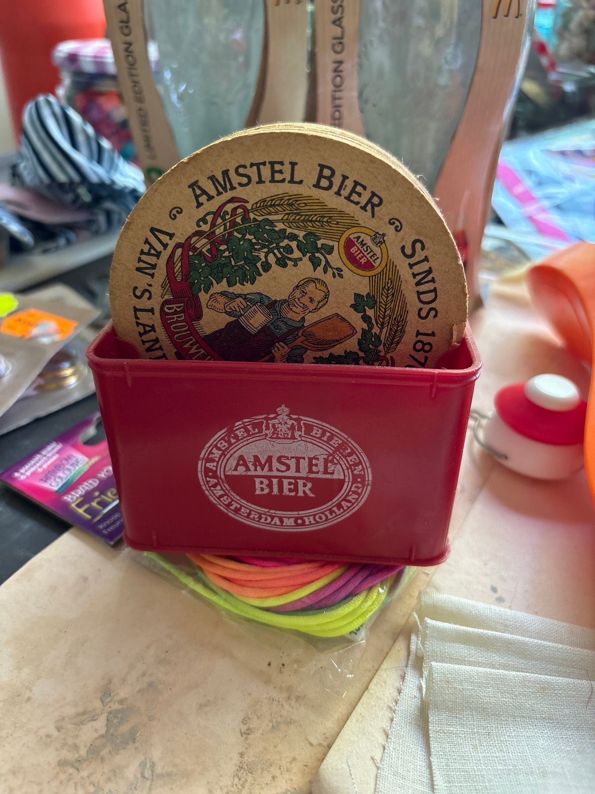 Amstel Bier viltjes in houder - verkleurd door krant, Ophalen of Verzenden, Gebruikt, Viltje(s), Amstel