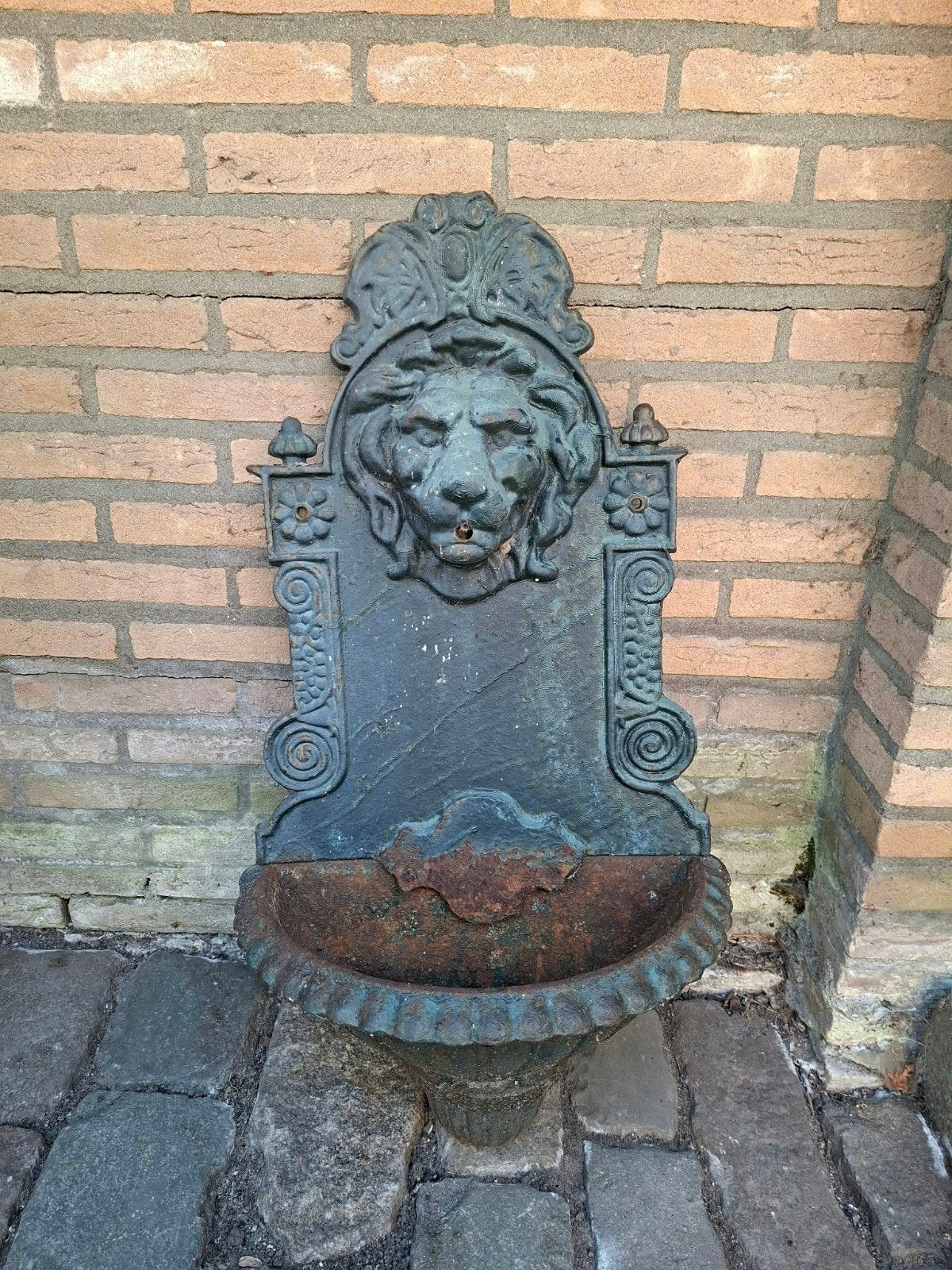 Antieke gietijzeren muurfontein met leeuwenkop, Ophalen