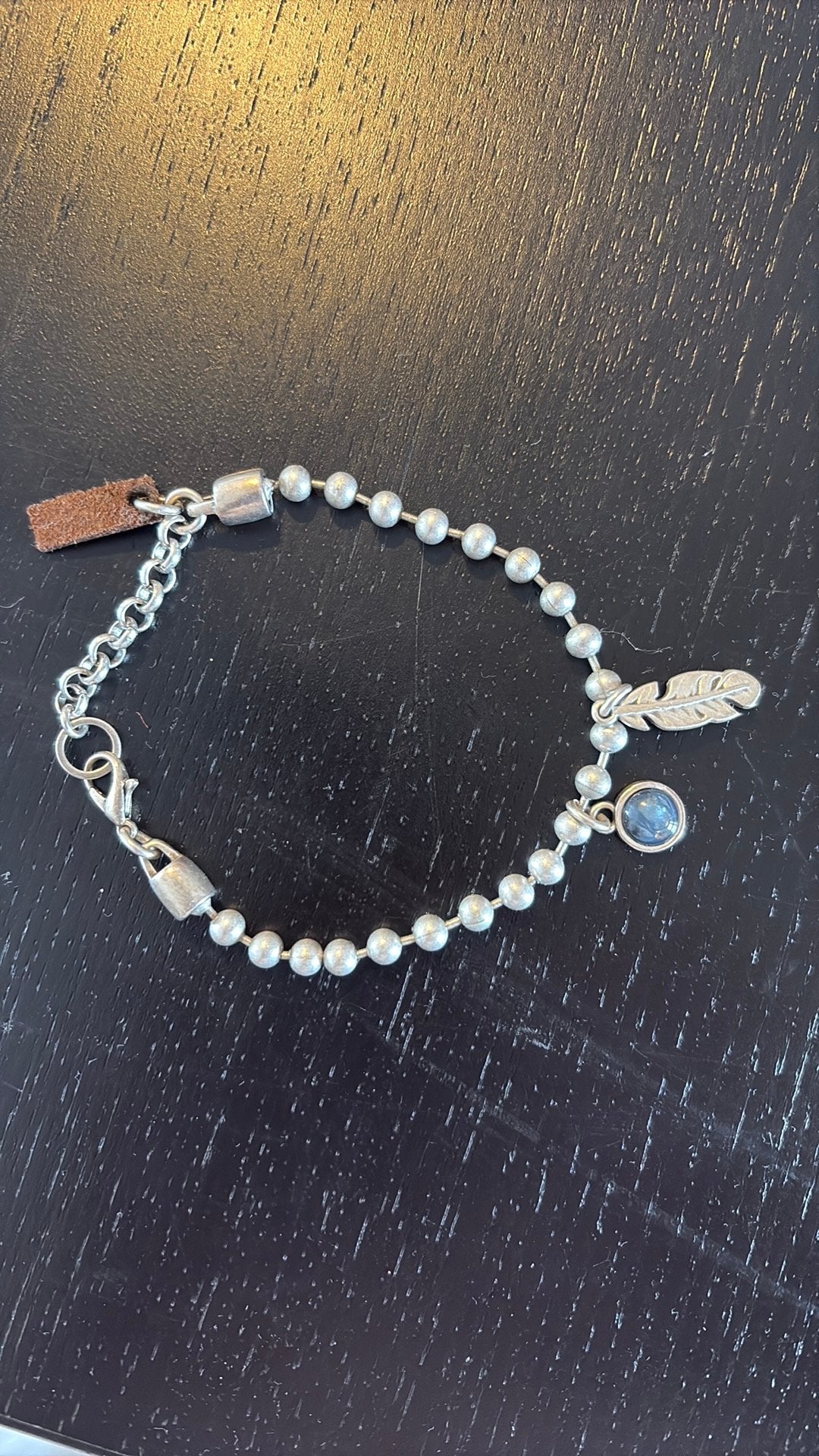 QOSS Zilverkleurige armband met veertje en blauwe steen, Ophalen, Overige materialen, Zo goed als nieuw, Met edelsteen