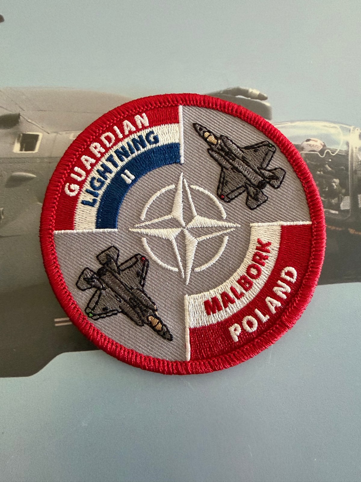 Guardian Lightning II Malbork Polen NATO 322 sqn, Verzamelen, Ophalen of Verzenden, Luchtmacht, Nederland, Embleem of Badge