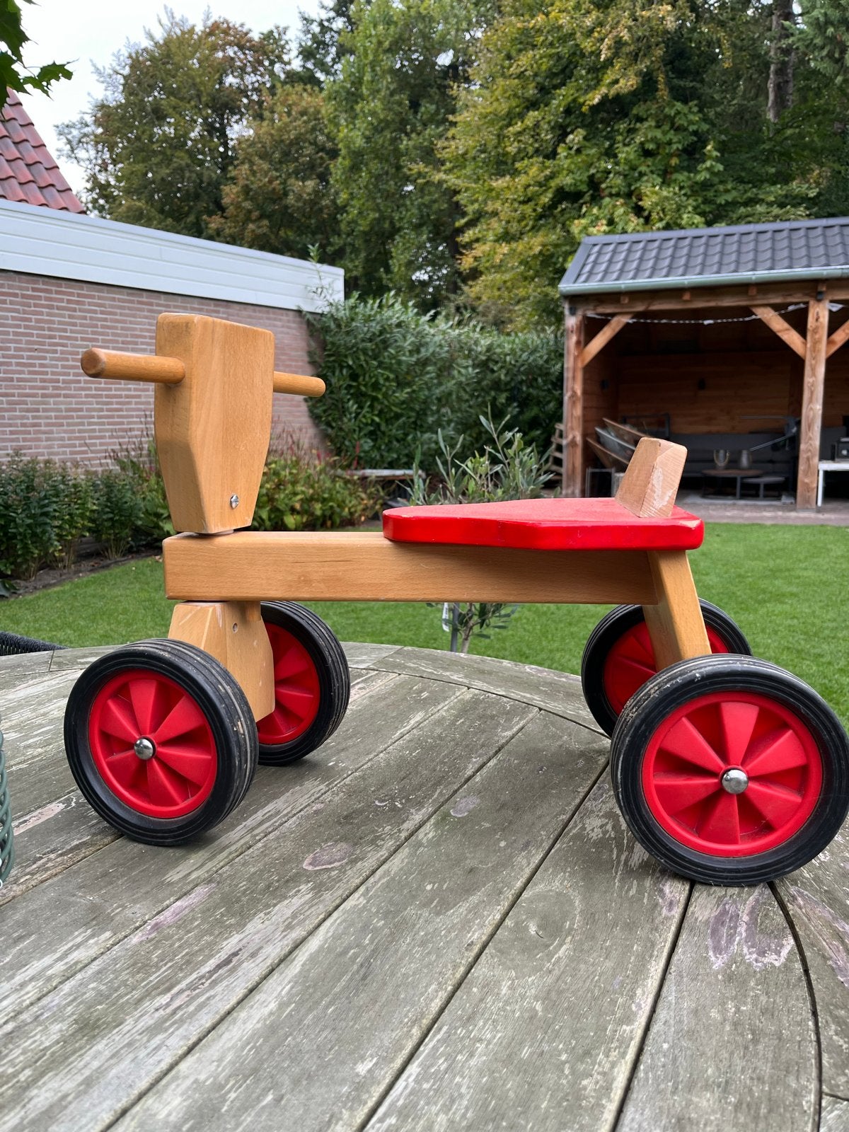 Houten loopfietsje met rode accenten