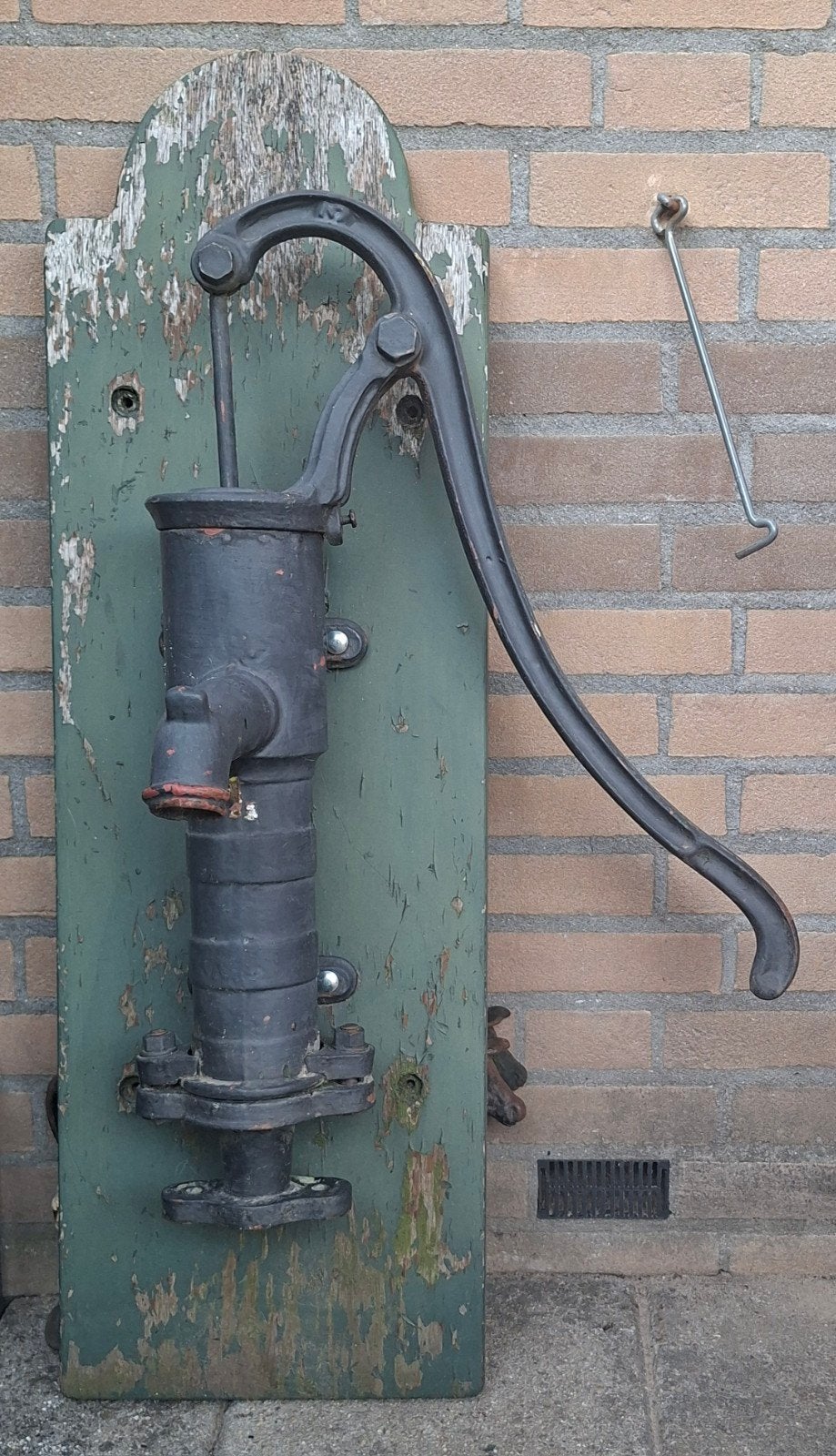 Gietijzeren waterpomp op verweerde houten plank, Ophalen