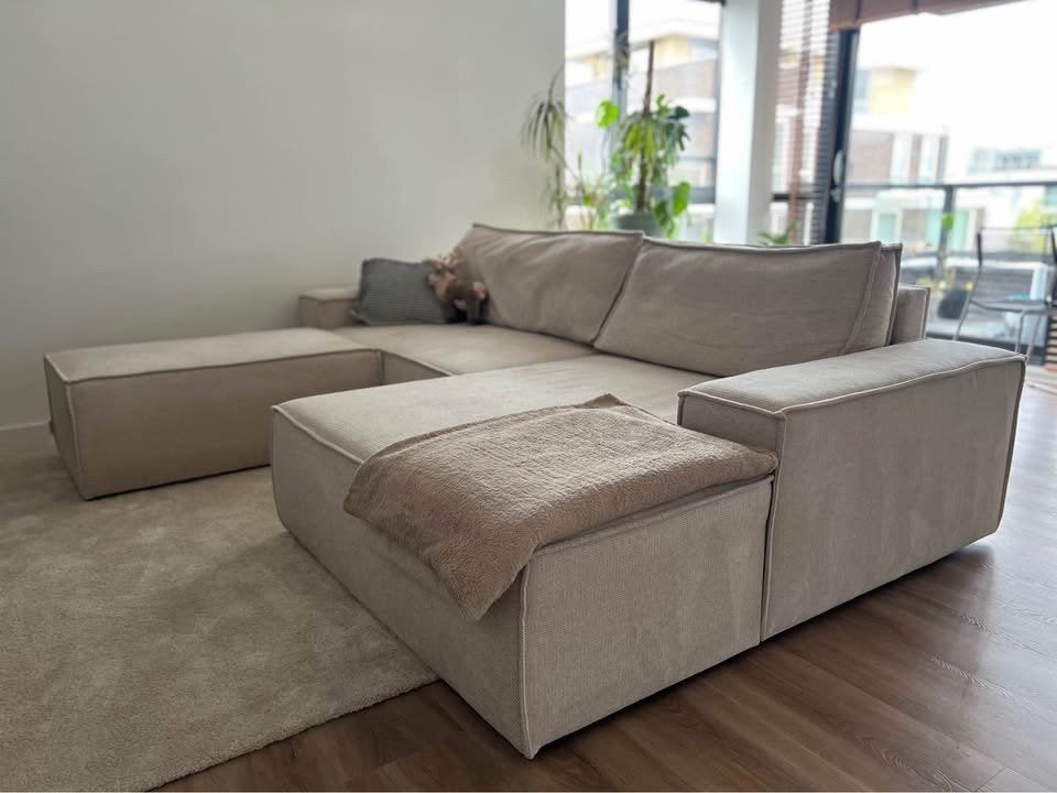 Brede hoekslaapbank van beige stof + poef, Ophalen, 125 cm of meer, Hout, 125 cm of meer
