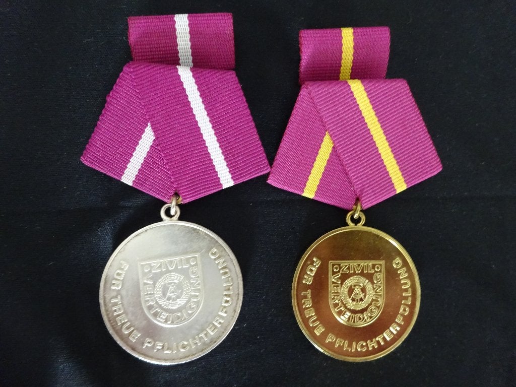 DDR:  Verdienstmedaille zilver en goud Zivilverteidigung, Ophalen of Verzenden, Landmacht, Duitsland, Embleem of Badge
