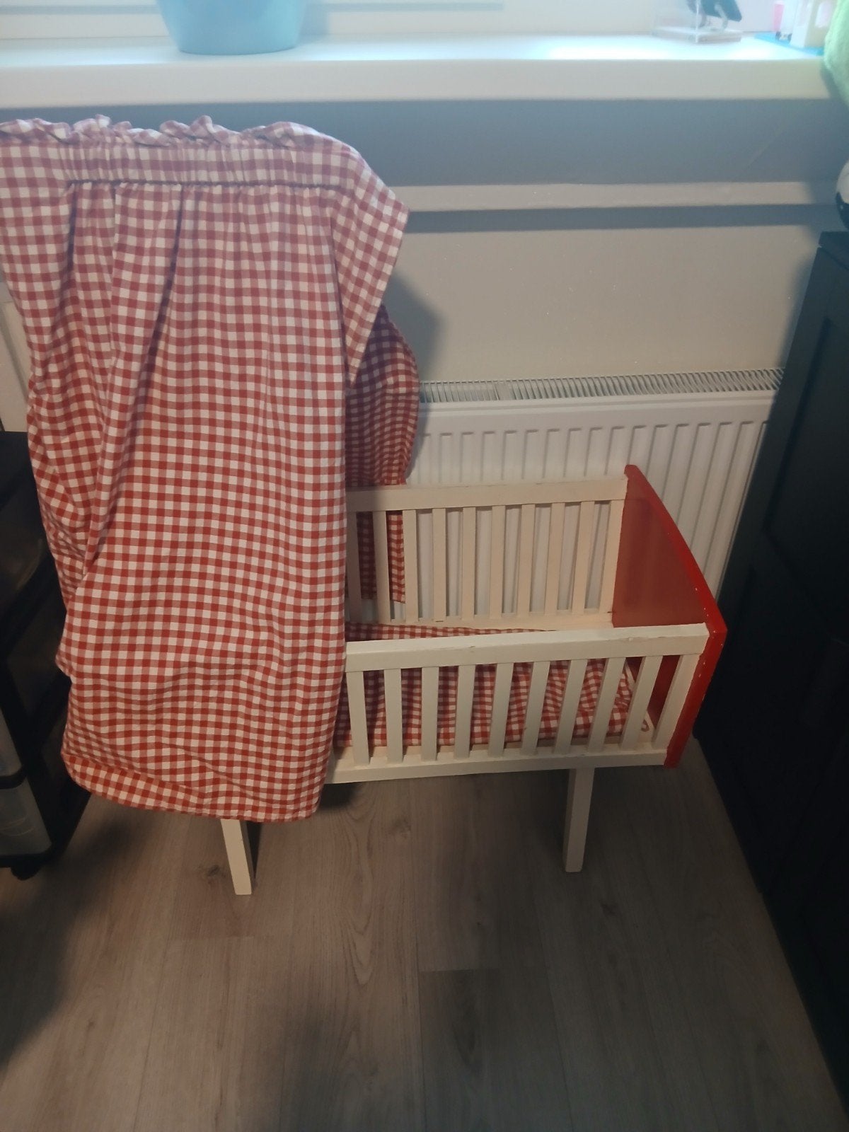 Houten poppenwiegje met rood-wit geruit beddengoed, Ophalen