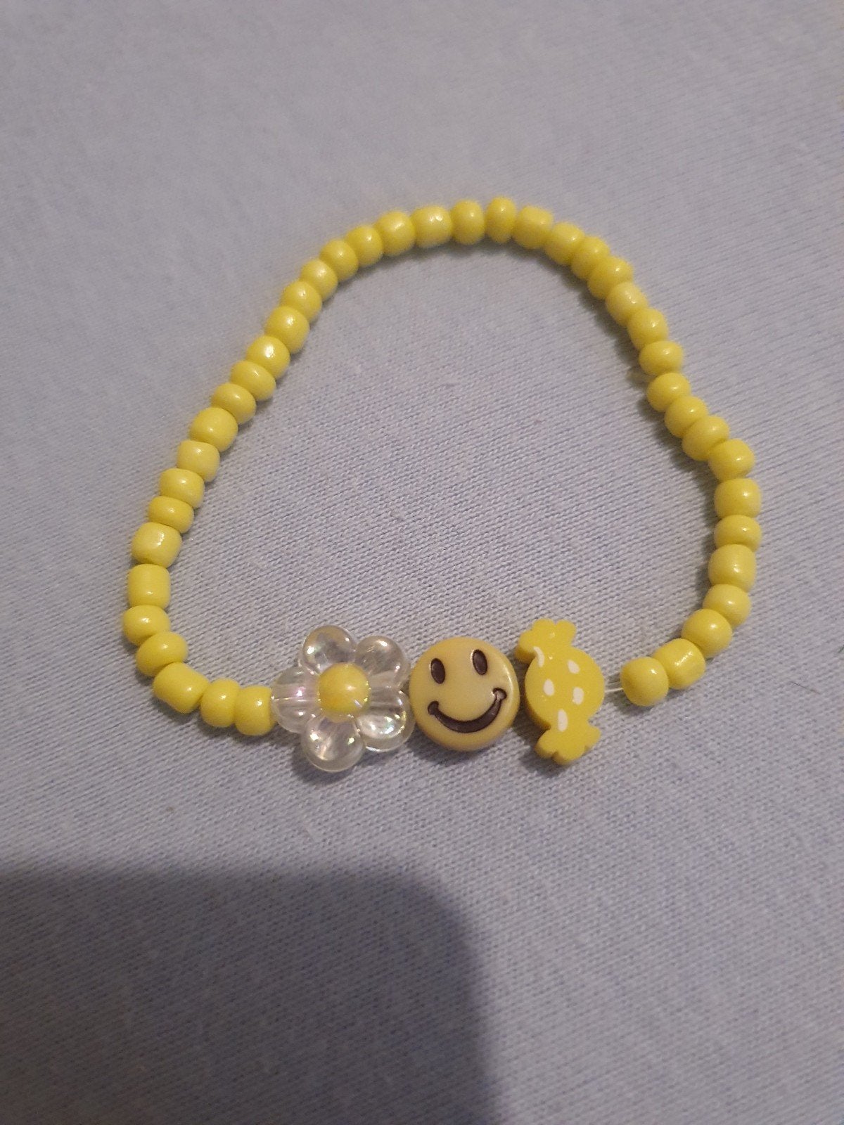 Geel kralenarmbandje met bloem, smiley en snoepje, Geel, Kunststof of Plastic, Ophalen of Verzenden, Zo goed als nieuw