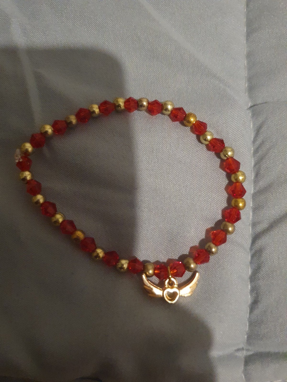 Rode en gouden kralenarmband met vleugelbedel, Overige materialen, Nieuw, Ophalen of Verzenden, Met bedels of kralen