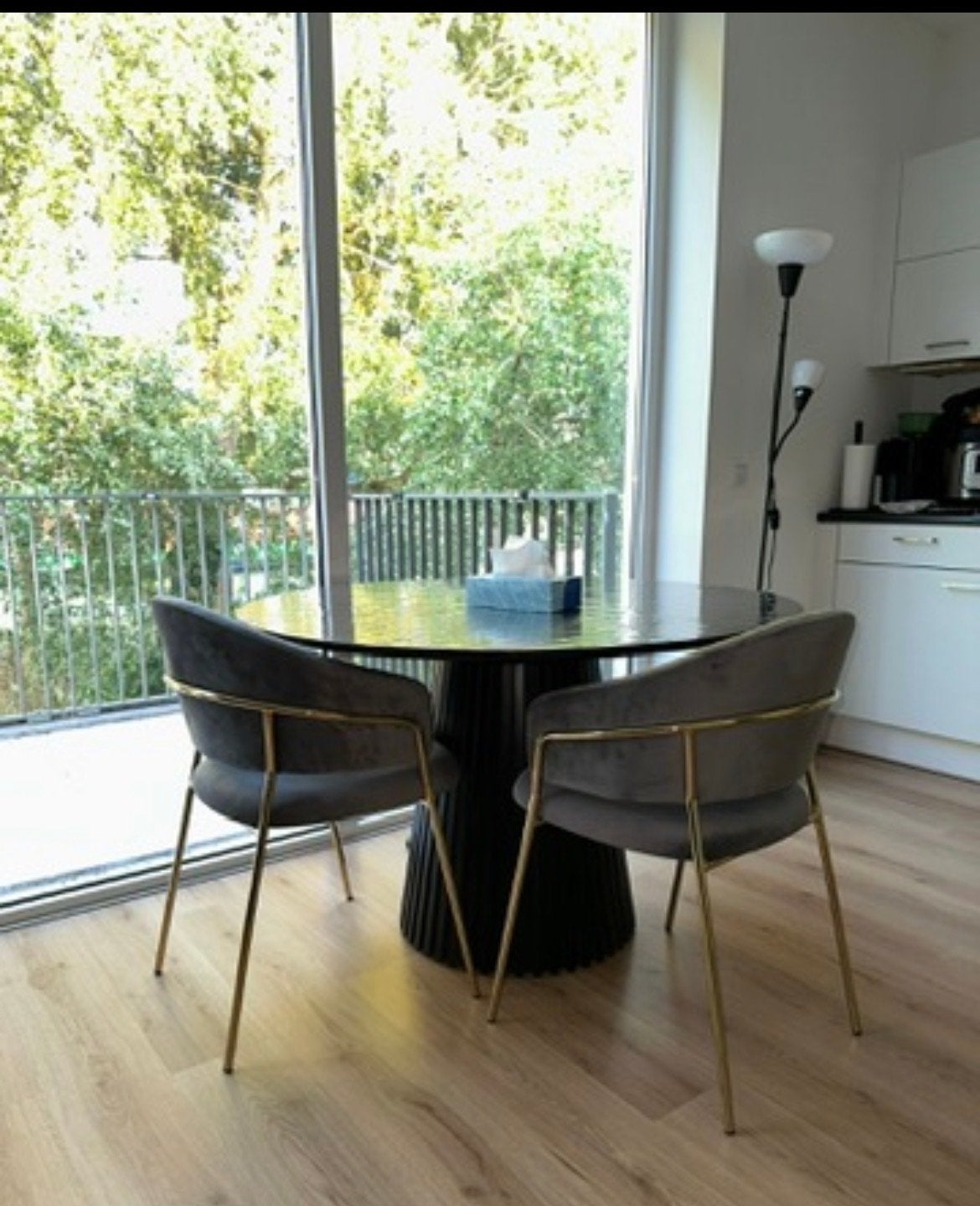 Ronde zwarte eettafel met vier fluwelen eetkamerstoelen