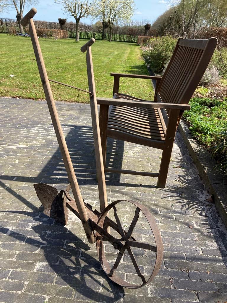 Oude handploeg met houten handvatten en ijzeren wiel, Ophalen